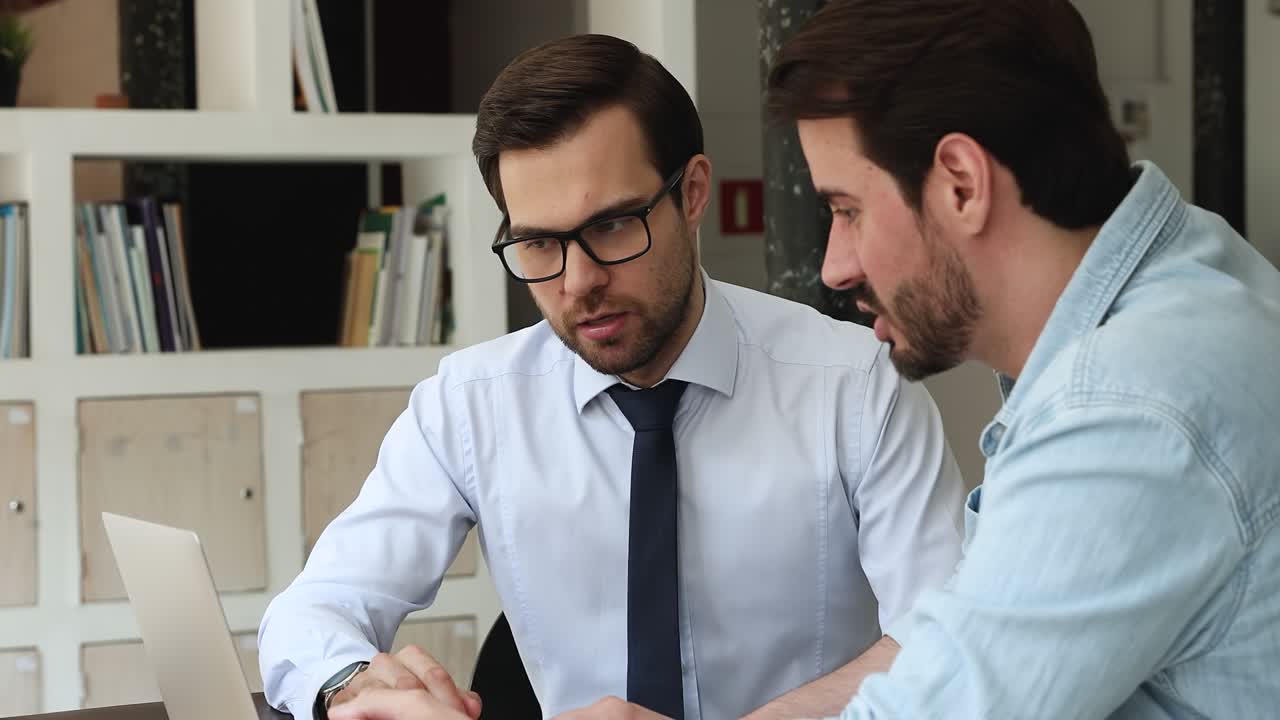 Two colleagues discuss online presentation collaborative project use laptop