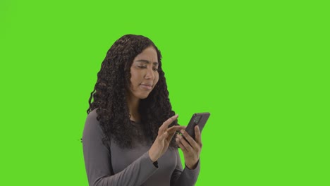 mujer esperando mirando el teléfono móvil contra la pantalla verde