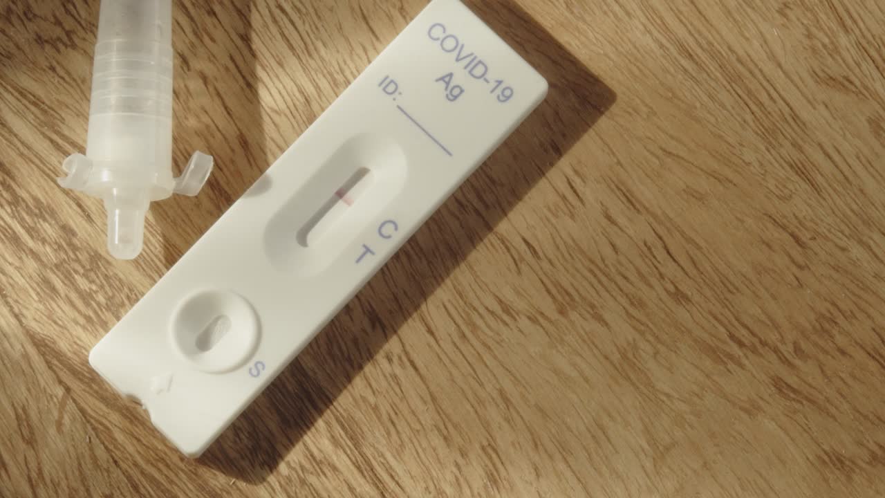 Pan across COVID-19 antigen test on wood table, high angle