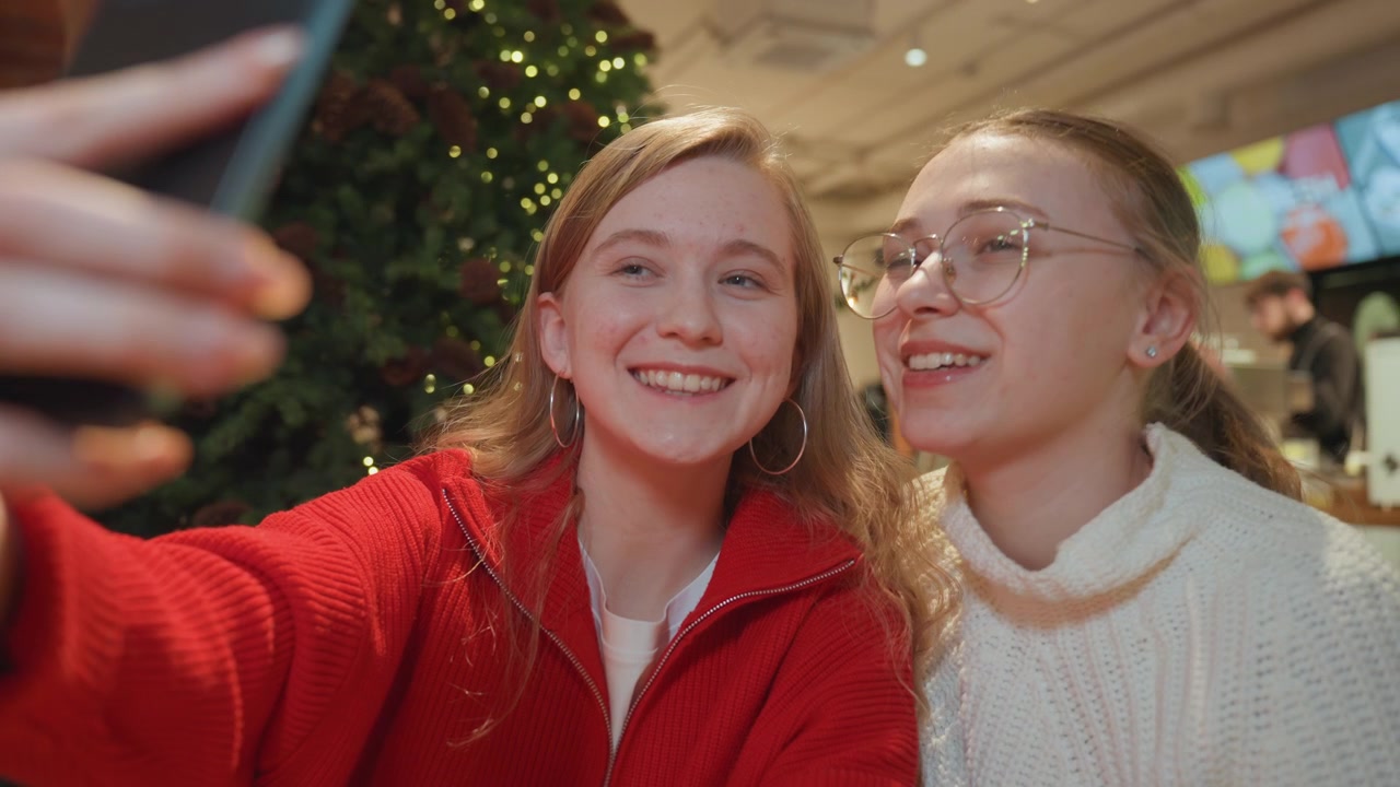 Młode kobiety pozujące do selfie w świątecznej kawiarni.