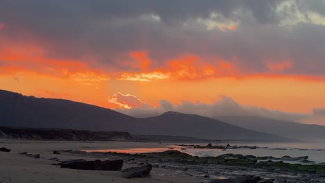 a rocky beach with the tide coming in during a magnificent sunset