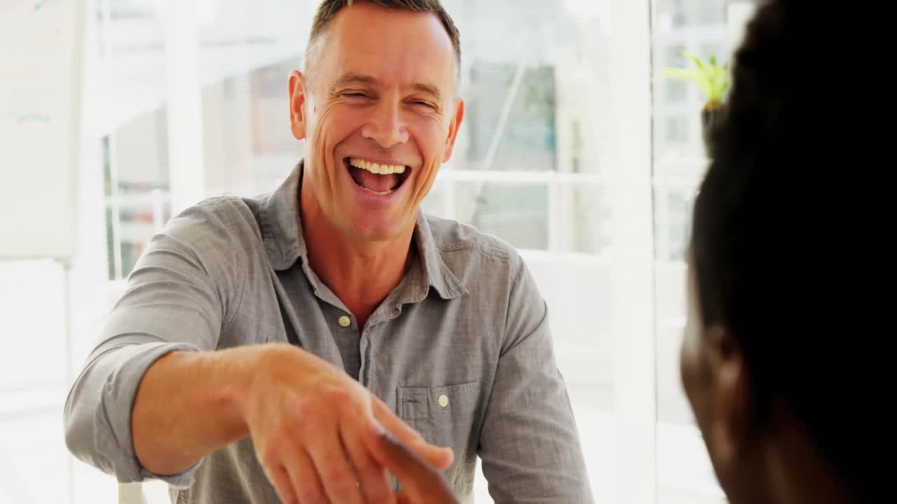 Forretningskolleger, der giver hånd på kontoret