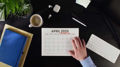 person planning for april 2025 on a desk calendar