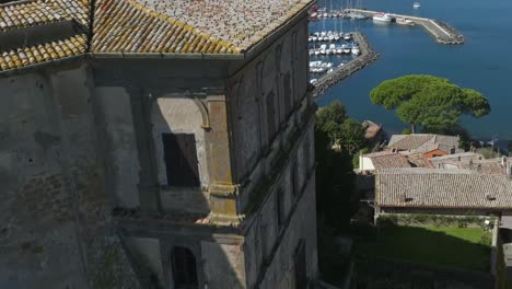 aerial over the marina at capodimonte and past the rocca farnese castle on lake bolsena, province of viterbo, italy