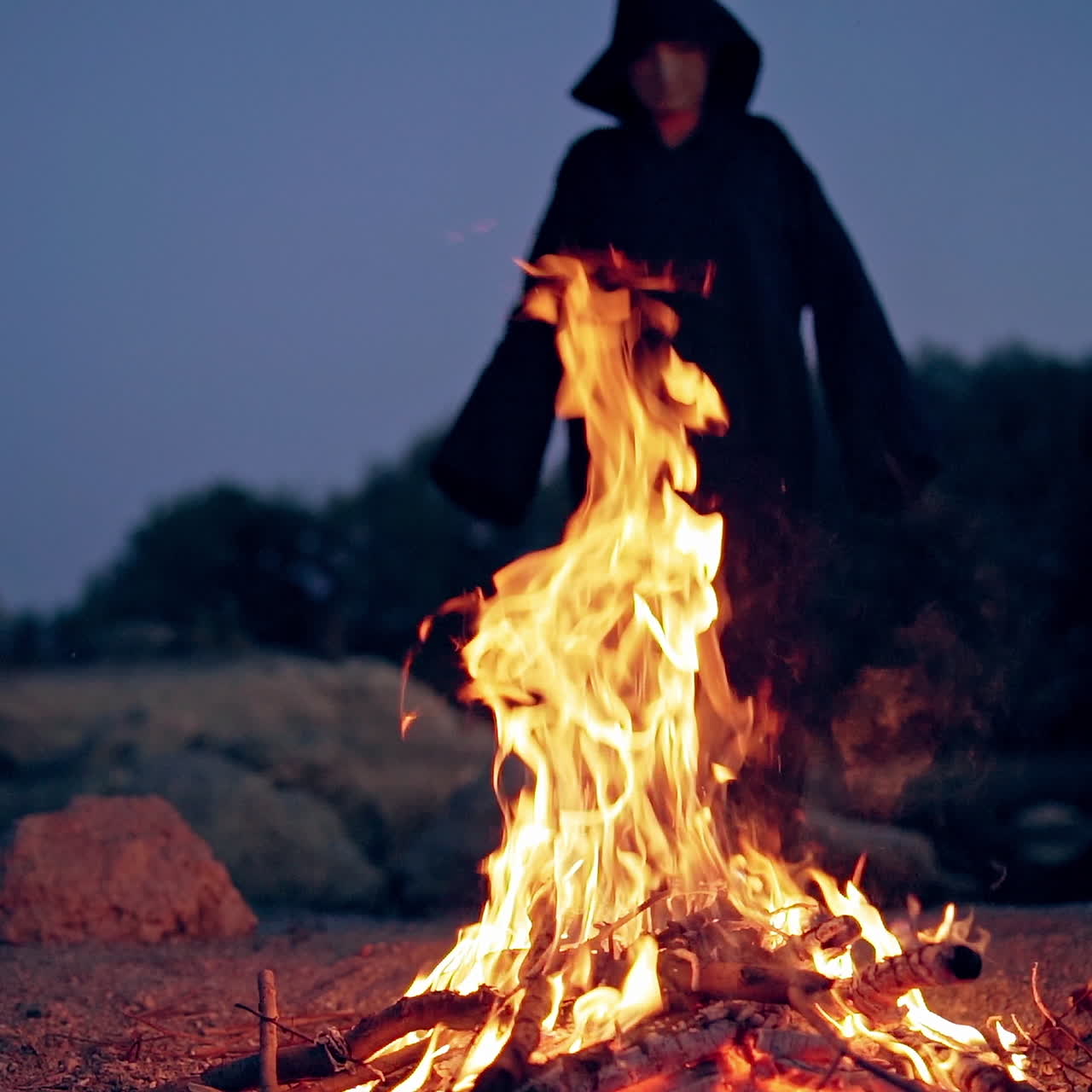 The old witch cooks a sorcery potion in the thicket of the forest. Fairy tales on Halloween. Burning fire.