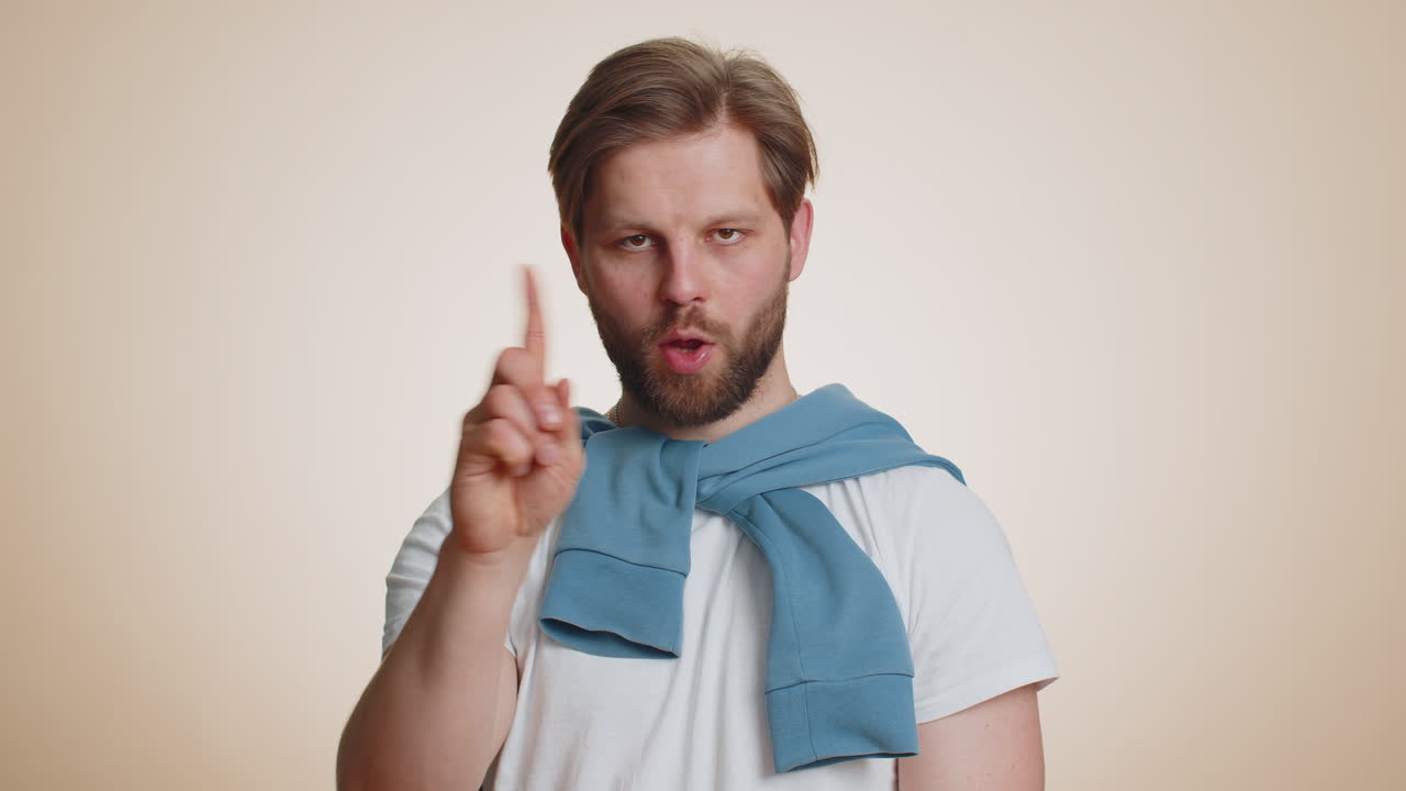 Caucasian young man shakes finger and saying no be careful avoid danger mistake disapproval sign