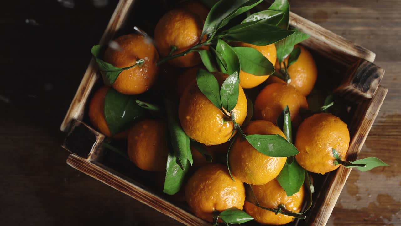 mandarinas con hojas en cajas de madera cayendo gotas de agua.
