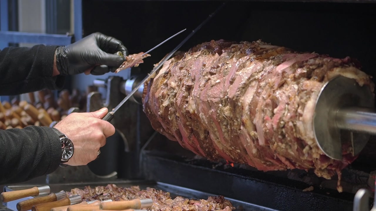 Chef Slicing Roasted Doner Kebab Meat from a Vertical Rotisserie