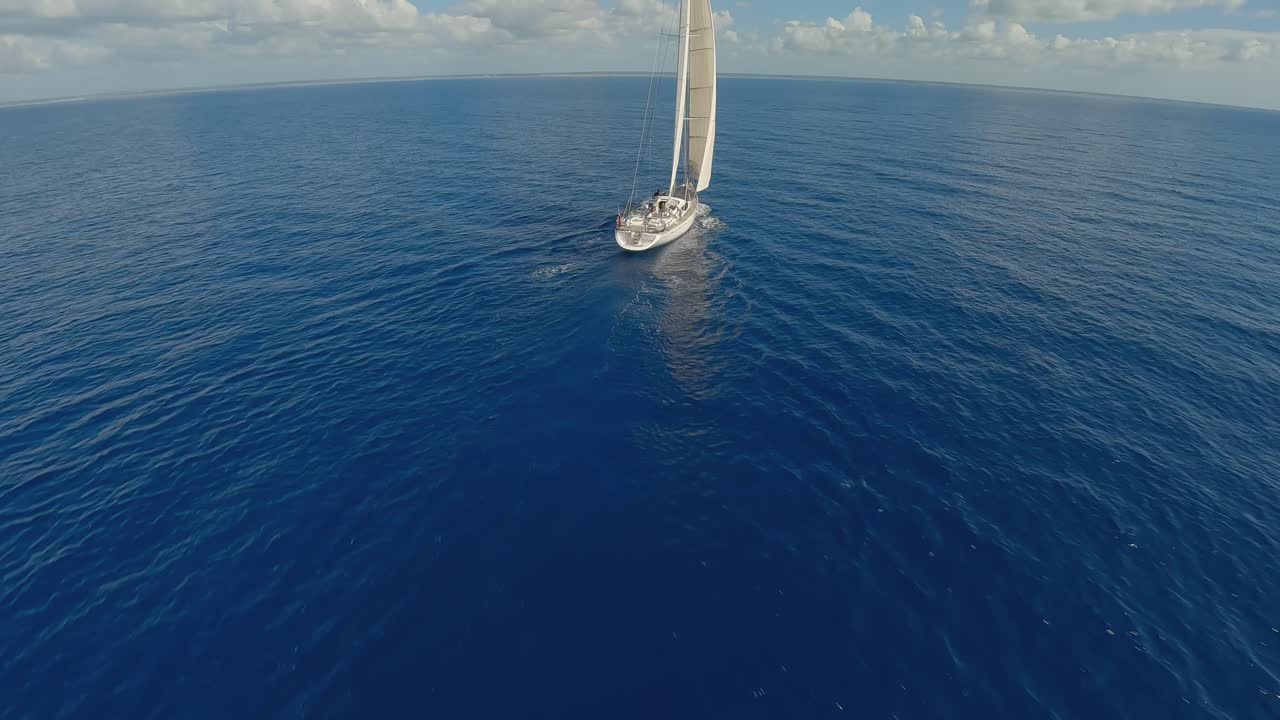 drone aéreo acrobático volando alrededor de un lujoso yate de ostras blancas 82 navegando en aguas azules del océano con horizonte en el fondo
