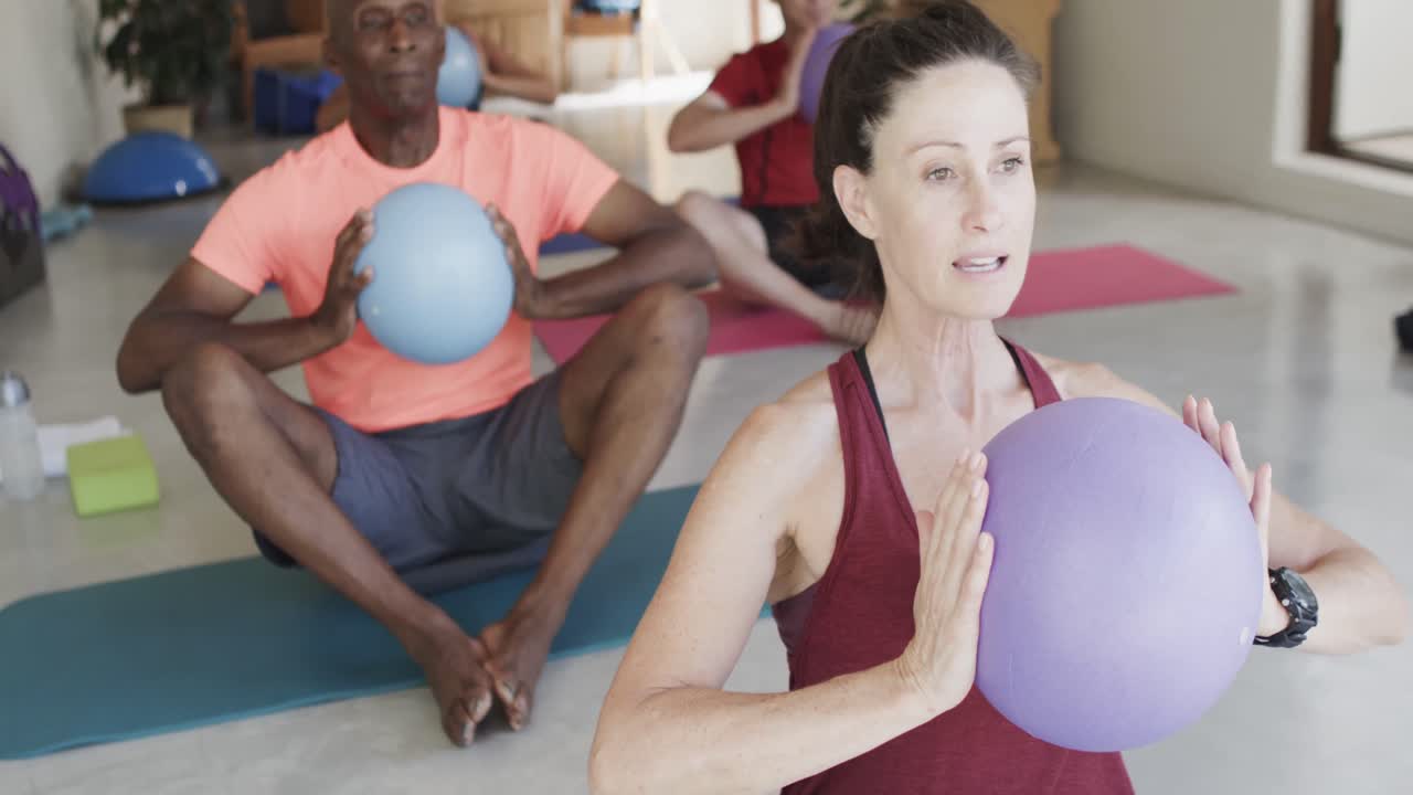 varios ancianos sosteniendo pelotas haciendo ejercicio con una entrenadora de pilates, sin alteración, en cámara lenta