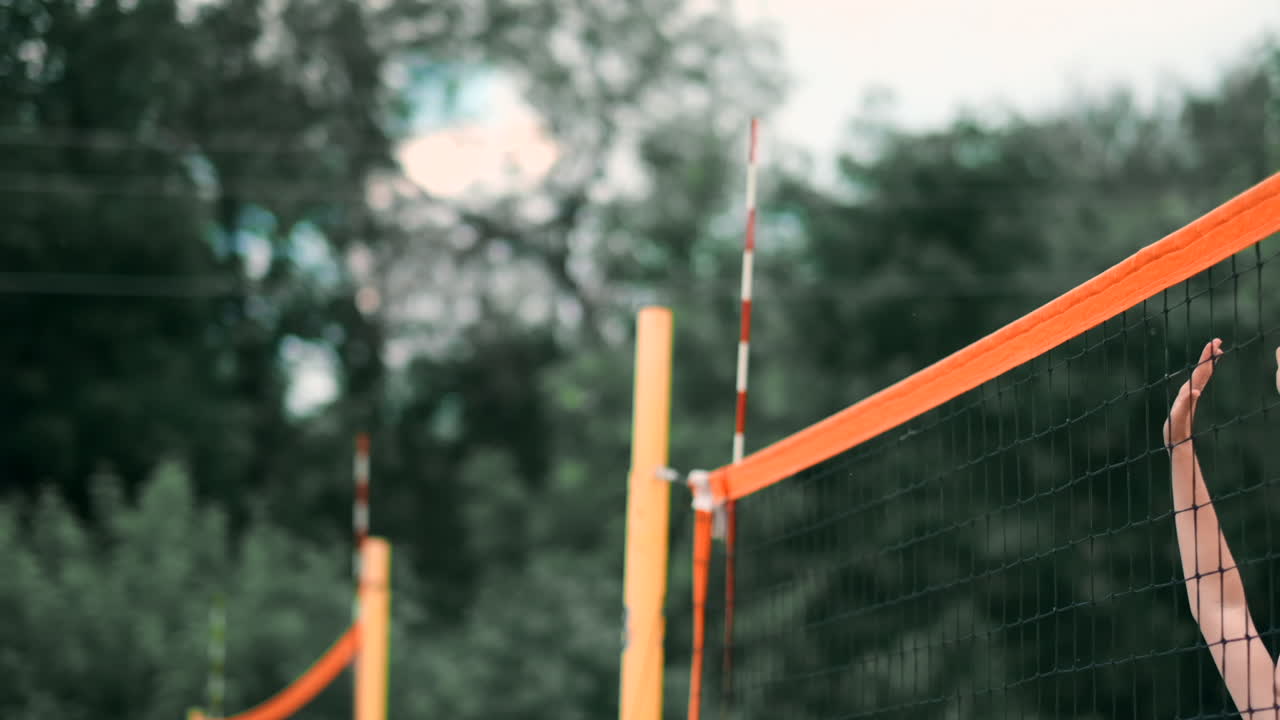 Women Competing in a Professional Beach Volleyball Tournament. A defender attempts to stop a shot during the 2 women international professional beach volleyball.