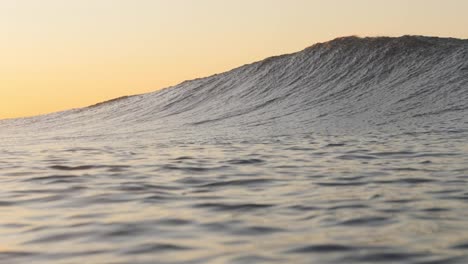 a beautiful wave breaks as the sun rises in the background