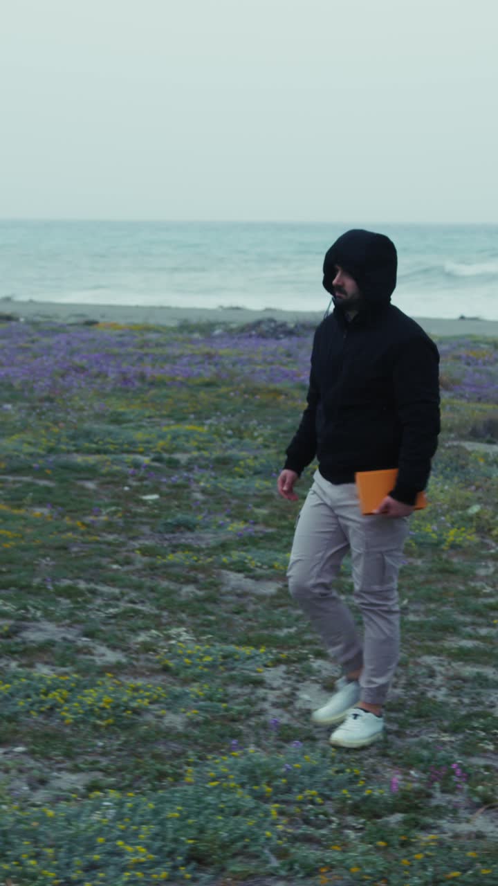 Man With Hoodie Walking Desolately On The Coast In Winter