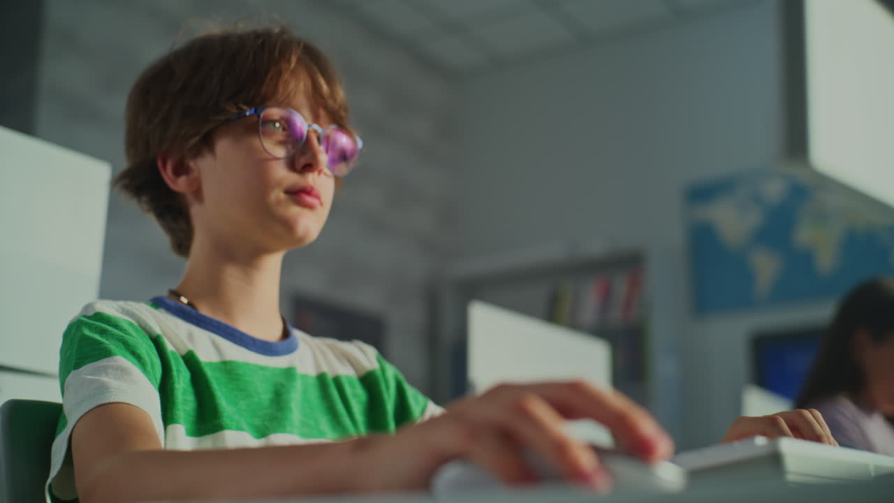 Boy in glasses using computer in a classroom