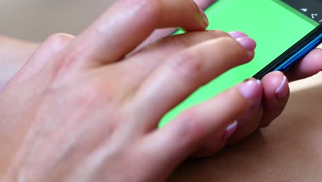 una mujer está sentada en un café con un teléfono inteligente en las manos con una maqueta de pantalla verde. la chica navega por internet, ve contenido, videos, blogs.