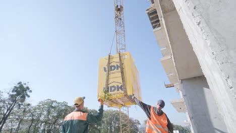 the construction crane lifts the white brick and transfers it to the construction site. a crane on a construction site lifts a load.