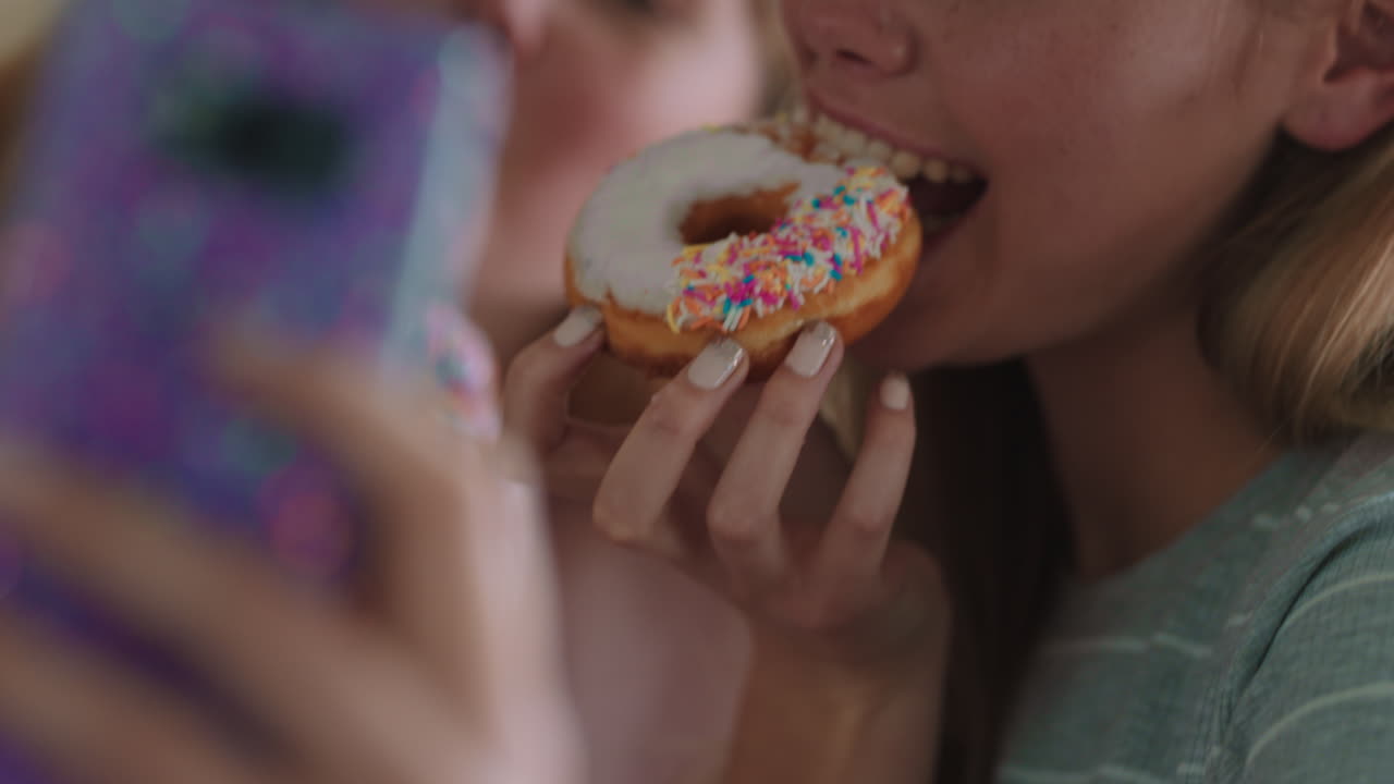 chicas adolescentes divertidas posando con rosquillas tomando fotos usando teléfonos inteligentes compartiendo en las redes sociales disfrutando de pasar el fin de semana en la cocina