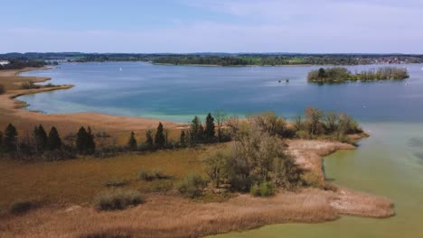 Scenic-high-flight-above-Bavaria's-famous-lake-Chiemsee-in-the-rural-countryside-with-a-beautiful-sky,-clear-blue-and-green-water-and-the-idyllic-Fraueninsel-in-the-background-on-a-sunny-day