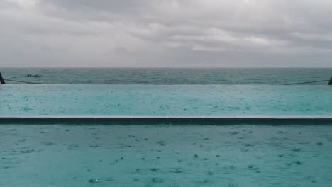 todavía clip de gotas de lluvia cayendo en la superficie del agua en una piscina al lado de la playa