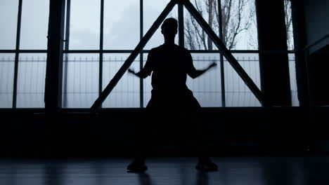 silueta de una bailarina practicando en un interior oscuro. hombre desconocido bailando en el interior.