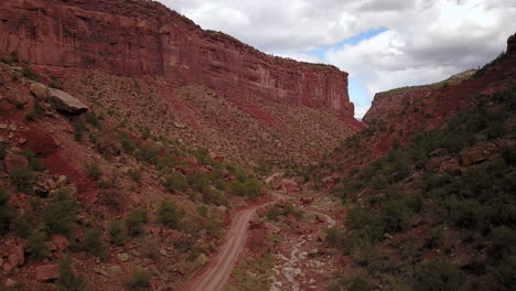 Aerial-of-dirt-road-with-Butte-Mesa-Flat-top-mountain-on-a-beautiful-day-in-desert-southwest-Colorado-USA