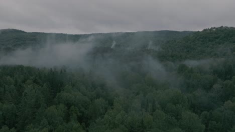 drone flying through a beautiful foggy mountain top landscape, pullout reveal