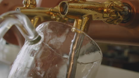 Tilt-down-on-barman-pulling-a-pint-of-foamy-beer-on-a-vintage-brass-and-golden-beer-tap