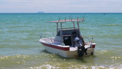 balanceándose sobre las ondas suaves y espumosas, un bote de velocidad anclado en las aguas poco profundas de la playa de pattaya en la provincia de chonburi, tailandia