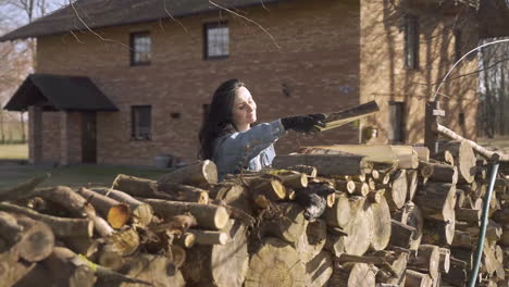 caucasian woman piling up firewood outside a country house