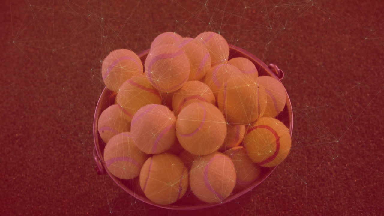 Metal bucket filled with tennis balls resting on dark court, showing red digital mesh overlay