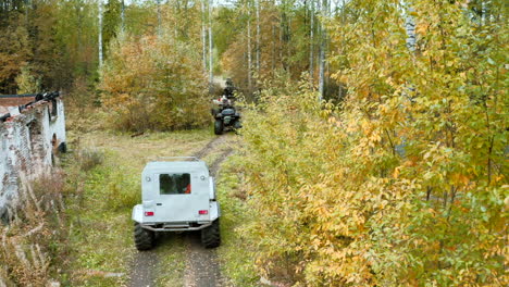 off-road vehicles in the autumn forest near an abandoned house