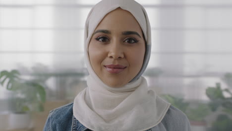 Primer-Plano-Retrato-De-Una-Joven-Mujer-De-Negocios-Musulmana-Mirando-La-Cámara-Sonriendo-Confiada-Usando-El-Tradicional-Pañuelo-Hajib-En-El-Fondo-Del-Espacio-De-Trabajo-De-Oficina