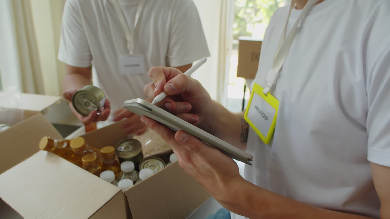 Unrecognizable Volunteers Filling Box with Food and Toiletry
