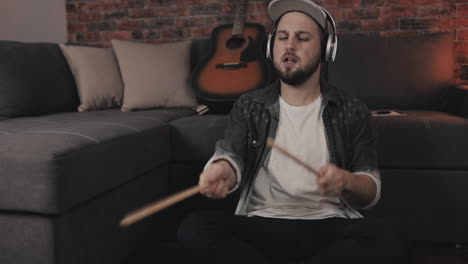 excited young man air drumming while listening to music at home