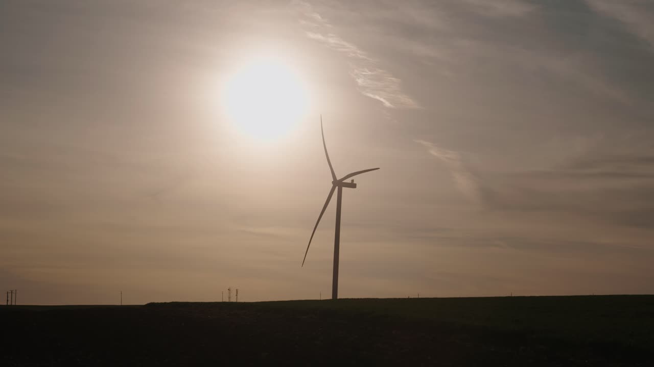 Silhouette of a Wind Turbine Against a Bright Sky