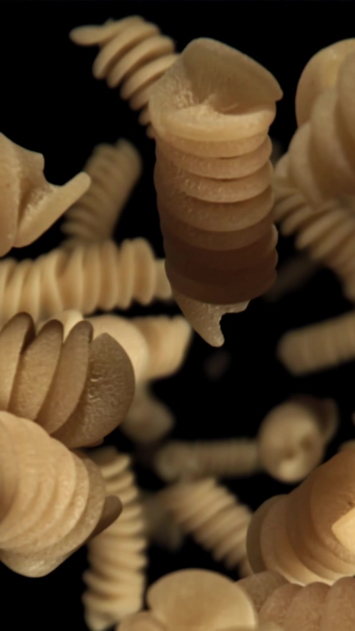 Slow Motion of Fusilli Pasta Falling Against a Black Background