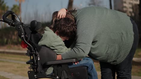 a woman hugging a child in a wheelchair in a park