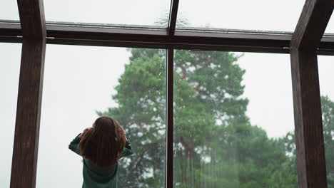 woman looking out window at rain