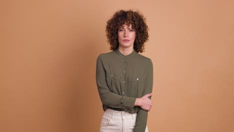 standing charming young woman with curly hair in beige background