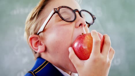 schoolboy eating apple in classroom