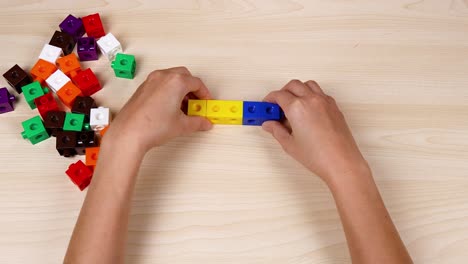 hands assembling colorful cubes on a table