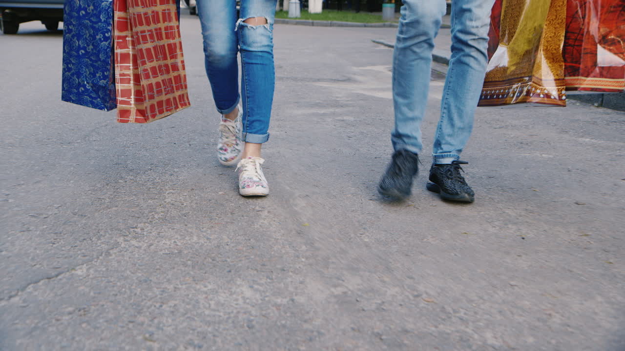 el hombre y la mujer están en la acera con bolsas de compras en la imagen solo se pueden ver las piernas hd vid