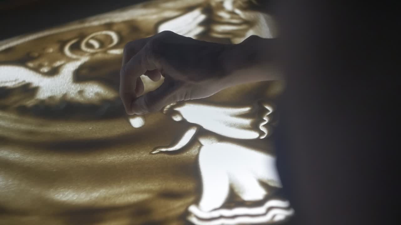 Female hands are painting on the sand