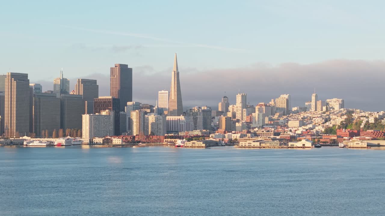 The San Francisco Embarcadero unfolds from above, showcasing a mosaic of buildings, piers, and shimmering water below.