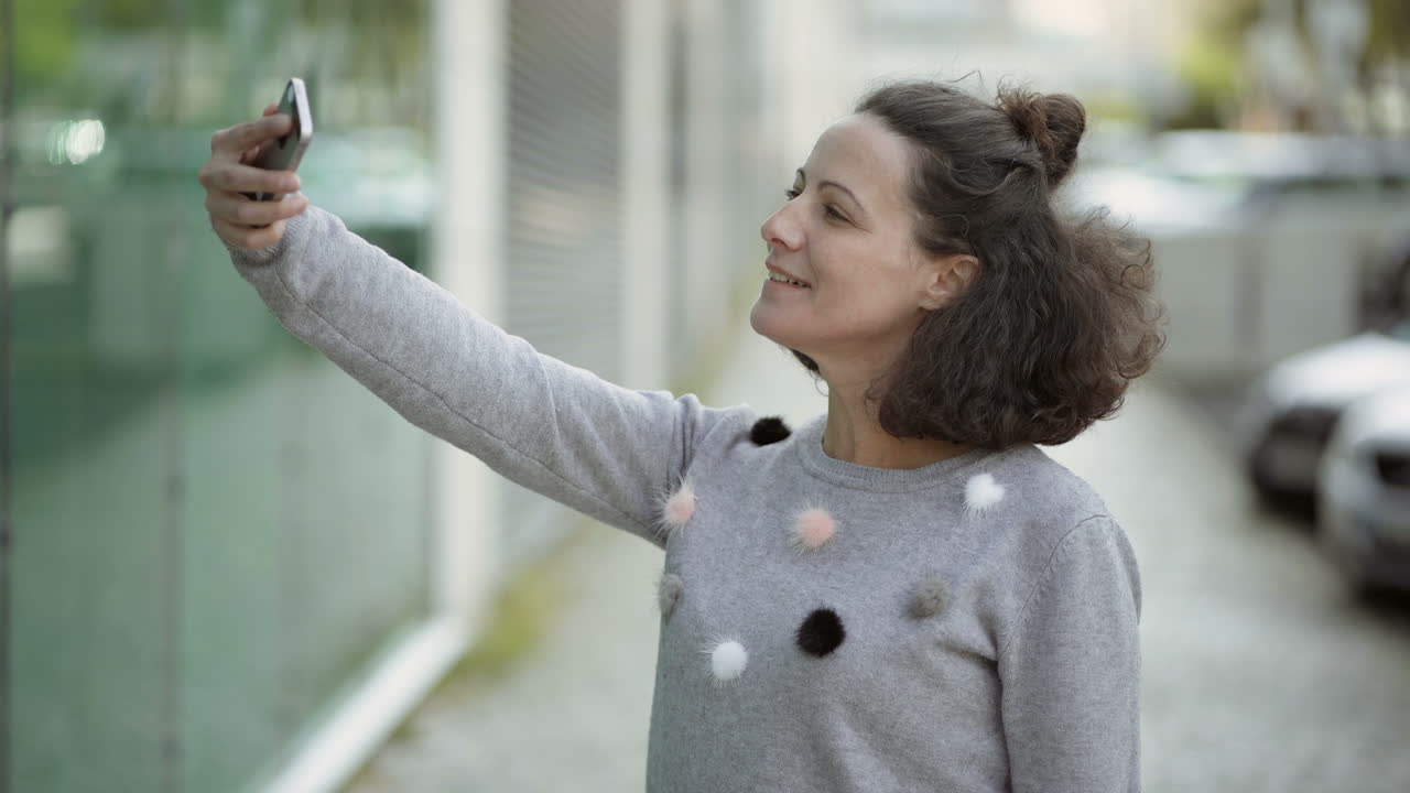 Attractive middle aged lady taking selfie with smartphone outdoor
