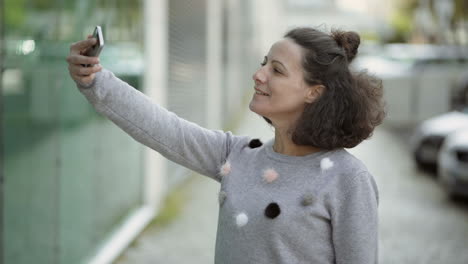 attractive middle aged lady taking selfie with smartphone outdoor