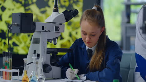 girl student in science laboratory using microscope