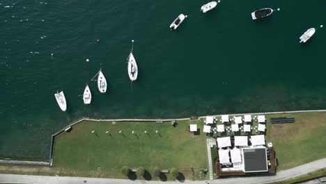 overhead drone shot of boats lining the shore of lake garda in italy.