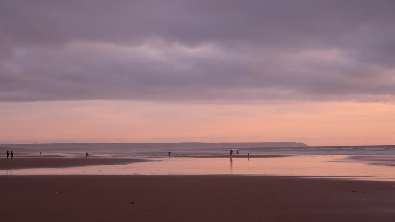 personas disfrutando de una puesta de sol pacífica y relajante en la playa con reflejos coloridos