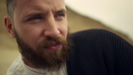 thoughtful man face looking away on nature background. handsome bearded guy.